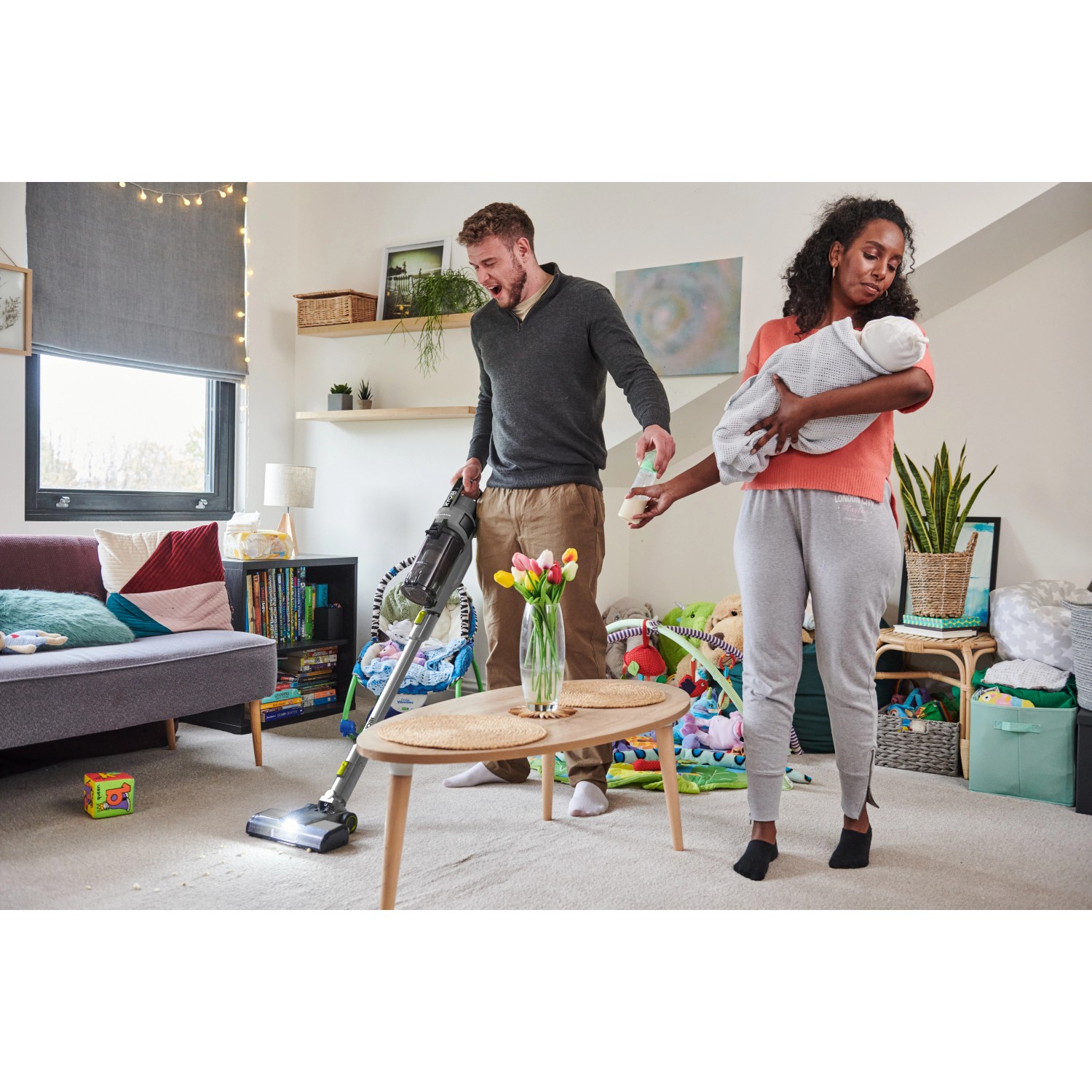 Ryobi Akku-Staubsauger RSVS18BL-0 im Einsatz: Mann saugt, Frau hält Baby. Ideal für die schnelle Reinigung.