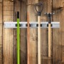 Silberne Aluminium-Gerätehalterleiste mit 4 schwarzen Klemmen an Holzwand, hält Besen, Schaufel und Rechen. Ordnungssystem für Gartenwerkzeuge.