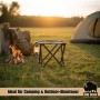 Schwarzer BigDean Falthocker mit vier Beinen im Gras vor Lagerfeuer und Zelt bei Sonnenuntergang. Ideal für Camping & Angeln.