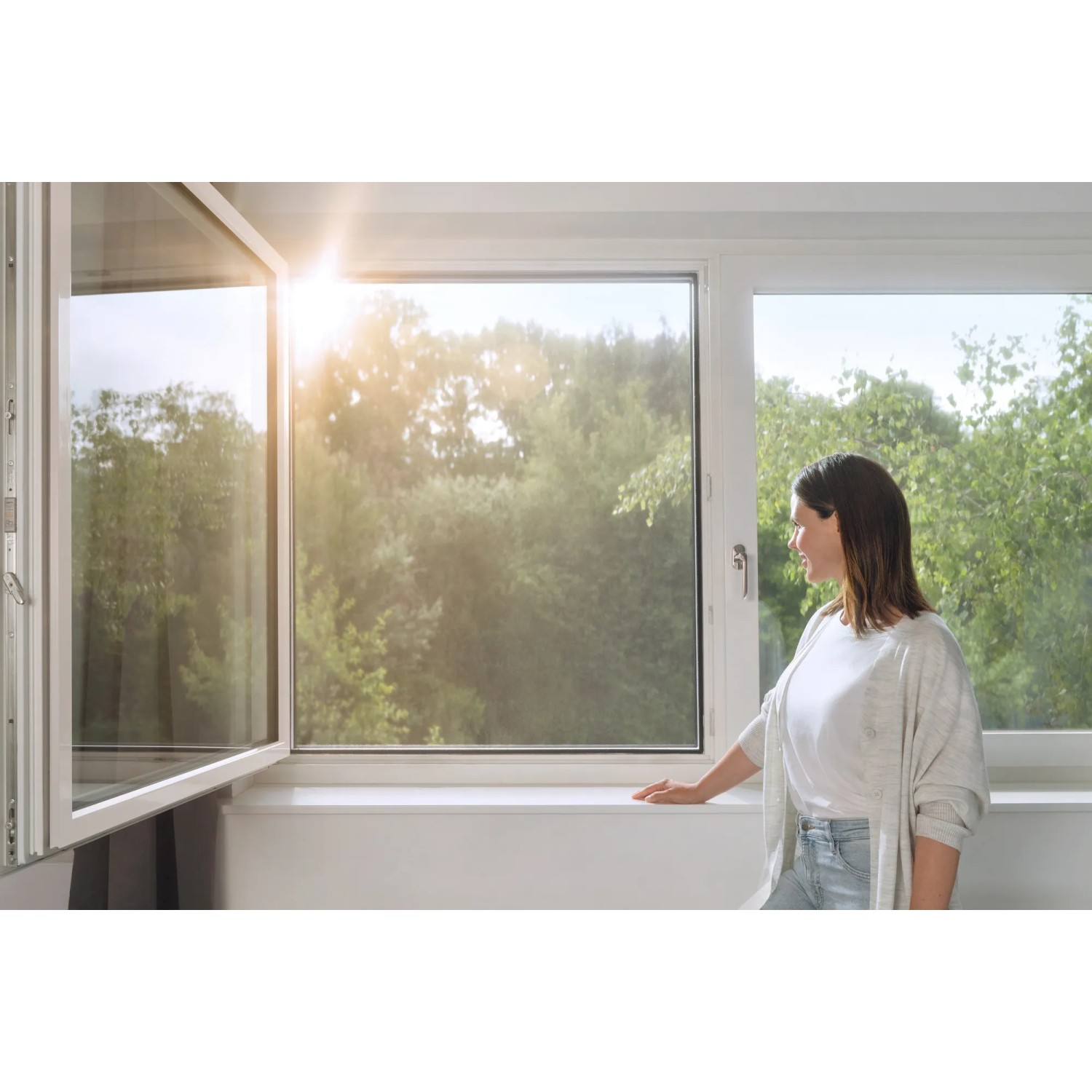 Frau am Fenster mit Tesa Pollenschutzgitter Anthrazit. Effektiver Schutz vor Pollen.