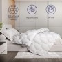 The White Stone Ganzjahresdecke 155x200 cm auf einem Bett. Weiche, weiße Bettdecke mit Rautenmuster.