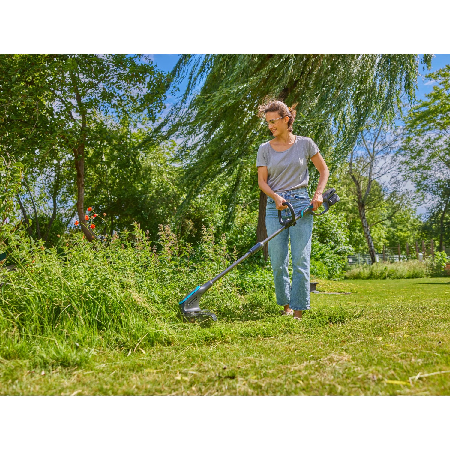 Frau nutzt Gardena Akku-Trimmer PowerTrim 30/18V im Garten für präzise Rasenkanten.