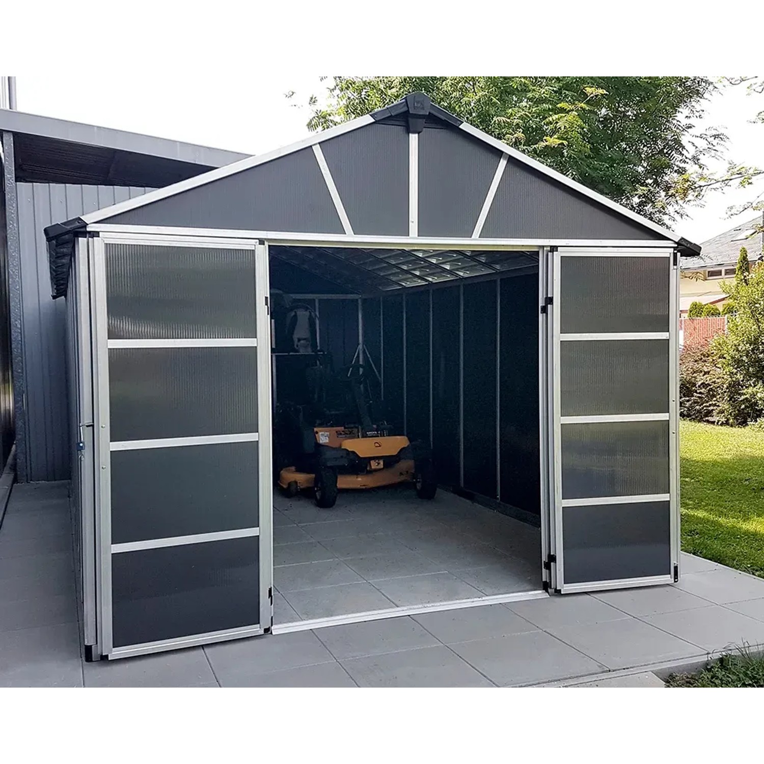 Palram Metall-Gerätehaus Yukon, 17,2 m², Anthrazit mit geöffneten Schiebetüren und Rasenmäher im Inneren.