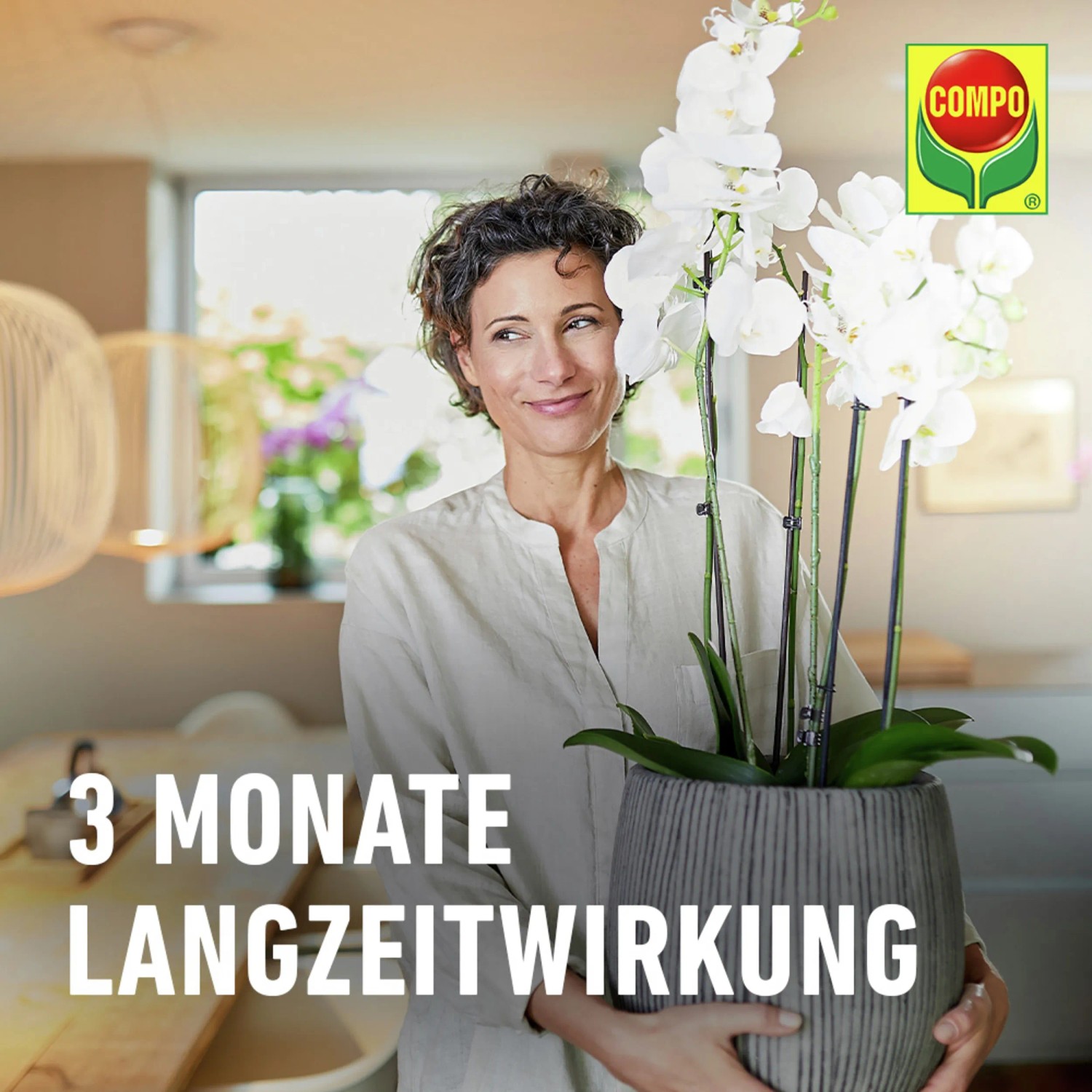 Frau hält blühende Orchidee im Topf, gedüngt mit Compo Düngestäbchen für Orchideen.