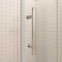 Detailaufnahme einer AICA Falttür Duschkabine mit Griff und 6mm ESG-Glas vor weiß gefliester Wand.