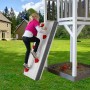Kind klettert an der weißen Sunny Spielhaus Kletterwand mit roten Griffen im Garten.