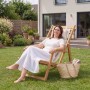Frau entspannt auf Juskys Akazienholz Strandliege Tavira (2er Set) in Creme im Garten.