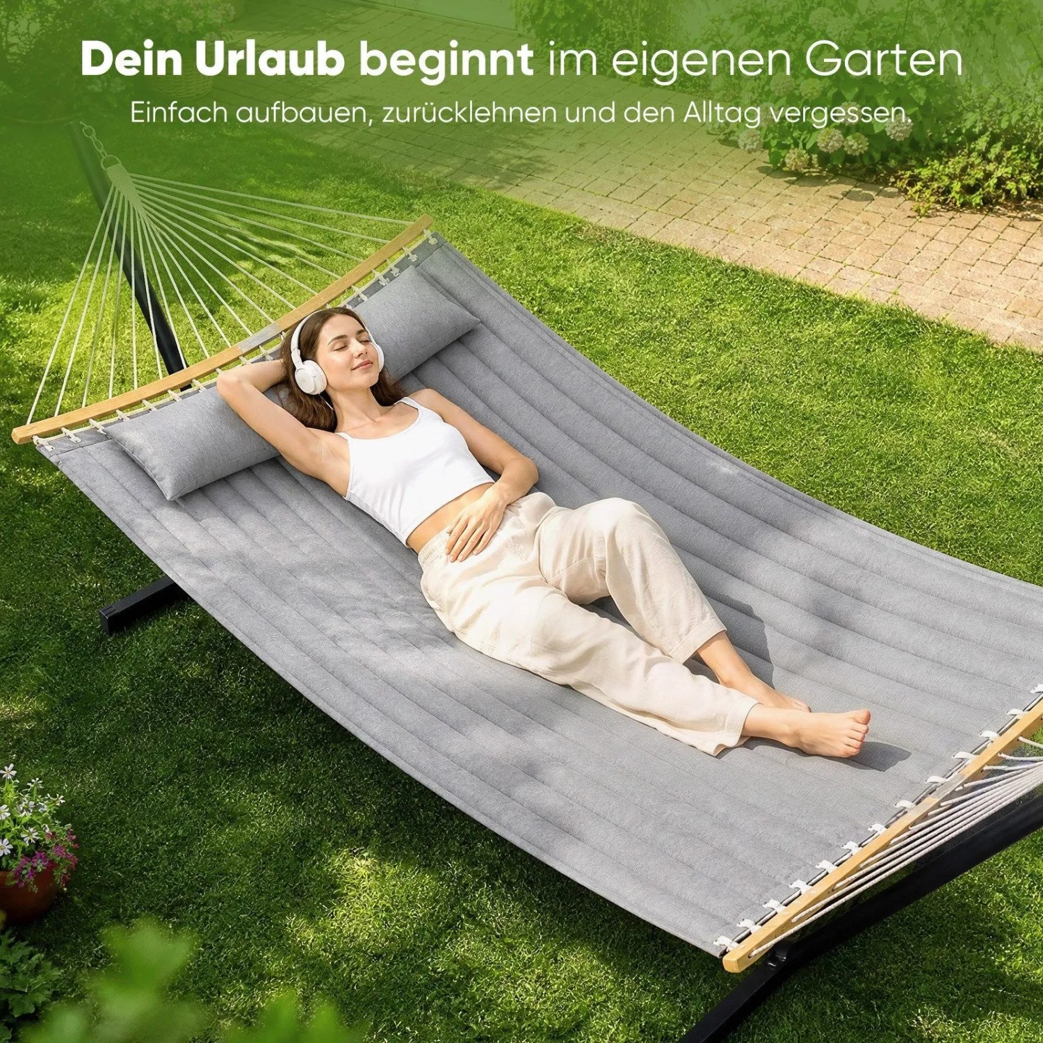 Frau entspannt in grauer, gepolsterter Doppelhängematte mit Kissen und Bambus-Spreizstäben im Garten. Ideal für 2 Personen.
