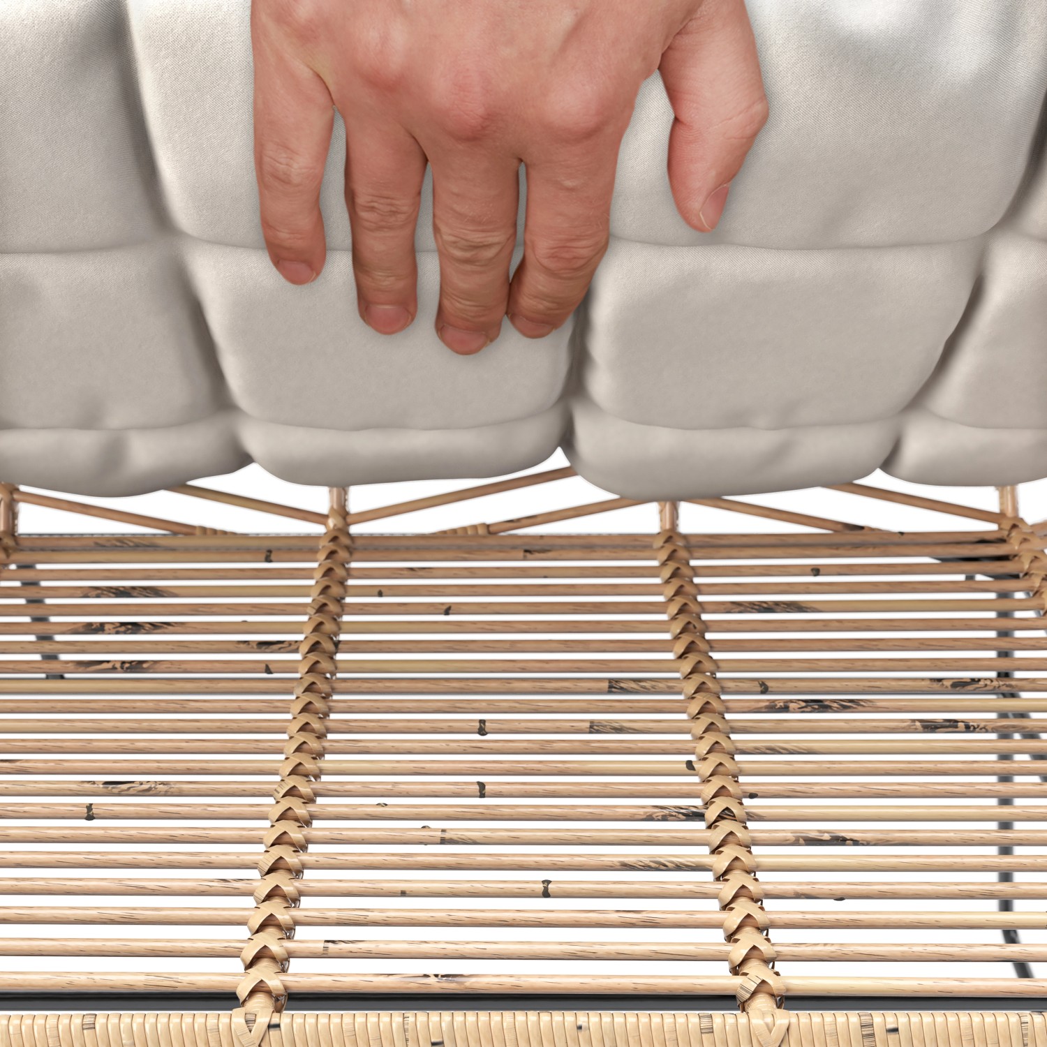 Detailaufnahme: Hand drückt auf Sitzkissen des 4-teiligen Lounge-Sets Udima aus Rattan.