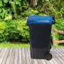 Graue Relaxdays Müllpresse aus Stahl mit Hebel an Mülltonne, Hände bedienen den Müllverdichter für Hausmüll.