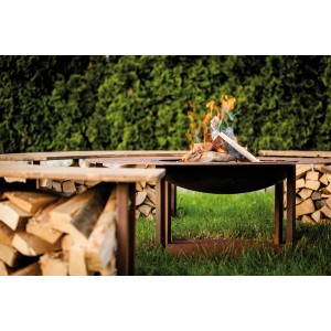 Ferrum Art Design Feuerstelle Circle Rost mit Feuer und Holzstapel im Garten.