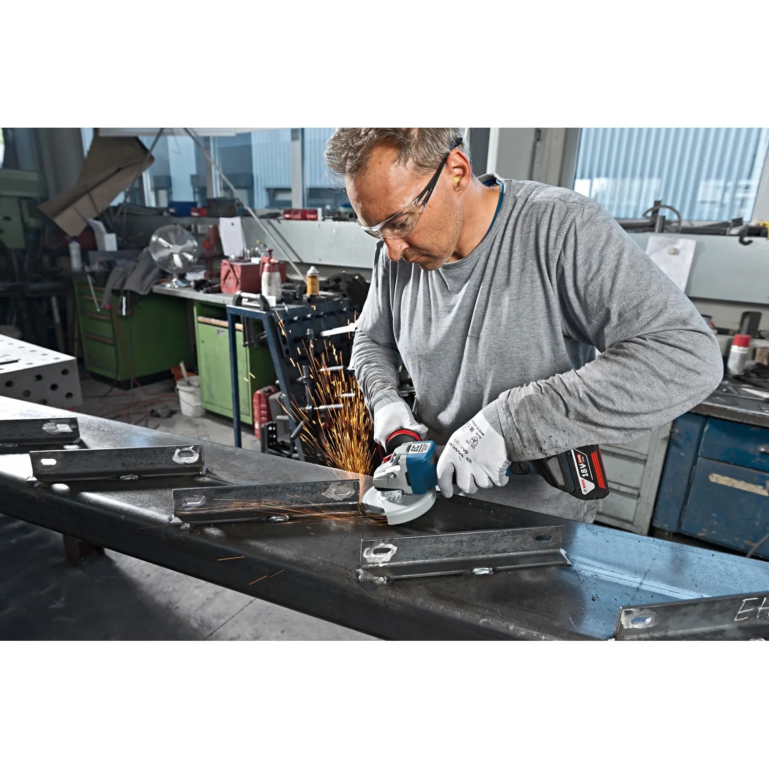 Mann schleift Metall mit Bosch Akku-Winkelschleifer GWS 18V-10 PC aus dem Combi-Kit.