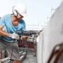Mann bohrt mit Bosch Hammerbohrer SDS Plus-3 ein Loch in eine Betonwand.