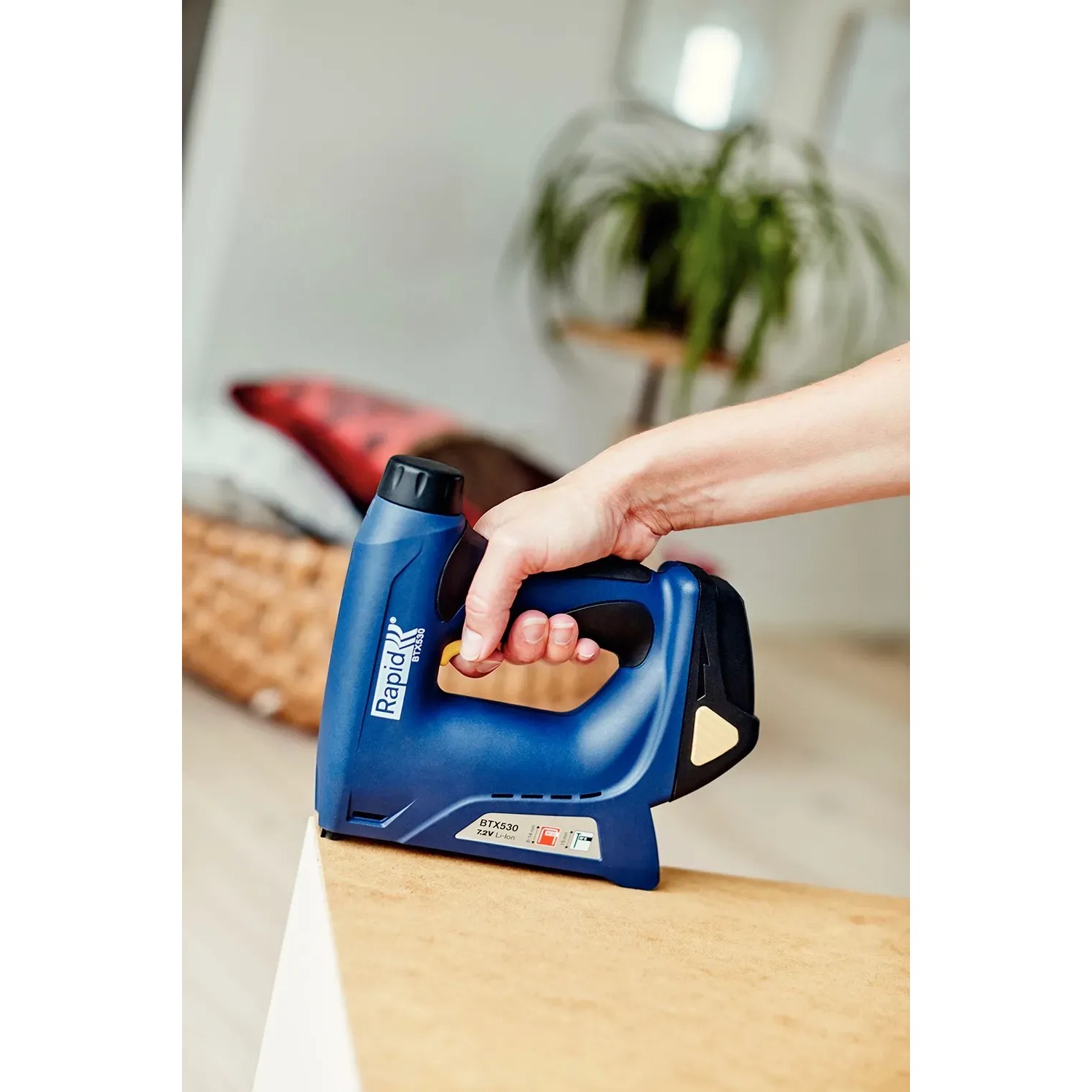 Rapid Akku-Tacker BTX530 in Aktion: Hand tackert Material mit blauem Tacker.