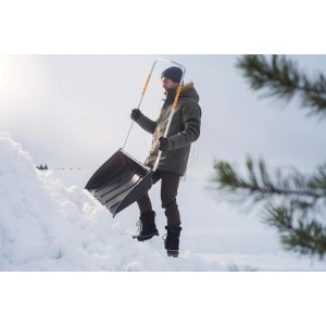 Mann mit Fiskars SnowXpert Schneewanne beim Schneeschieben.