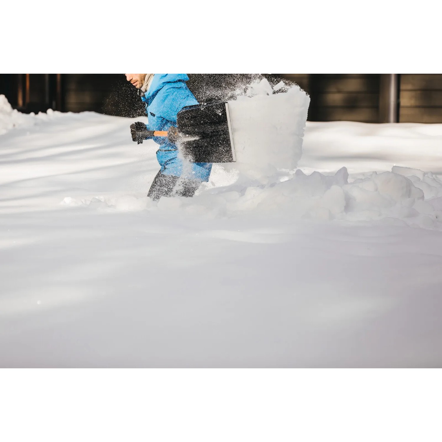 Person schaufelt Schnee mit der Fiskars Schneeschaufel Telescopic X-series.