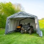 Graue ShelterLogic Garage-in-a-Box mit Rasentraktor und Quad im Grünen.