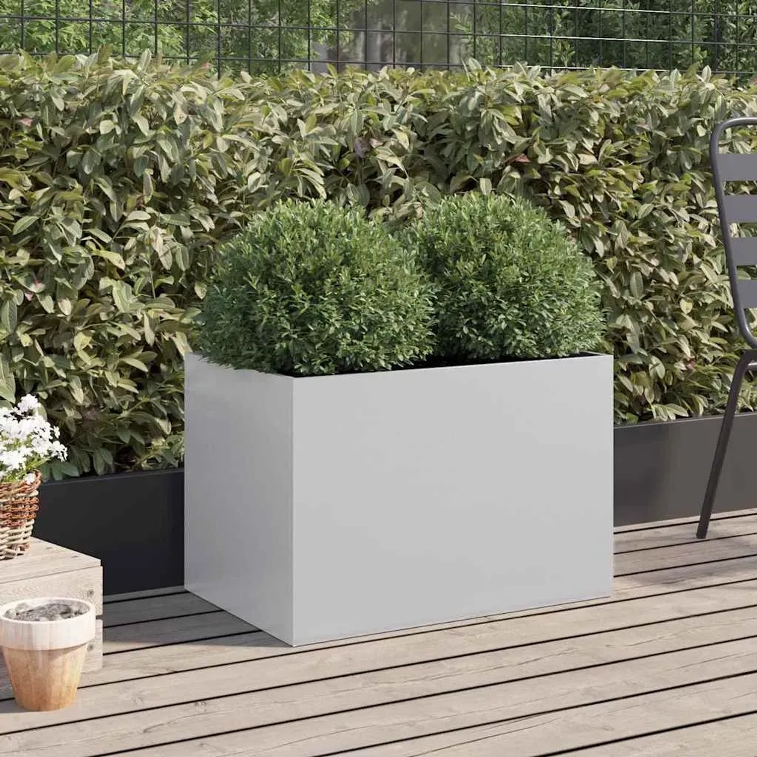 Silberner, rechteckiger Pflanzkübel aus verzinktem Stahl mit grünen Pflanzen auf Holzterrasse.