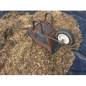 Schwarze Aquagart Unkrautfolie unter Holzhackschnitzeln mit Schubkarre im Garten.