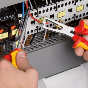Knipex Abisolierzange (160mm) im Einsatz beim Abisolieren eines Kabels in einem Schaltschrank.