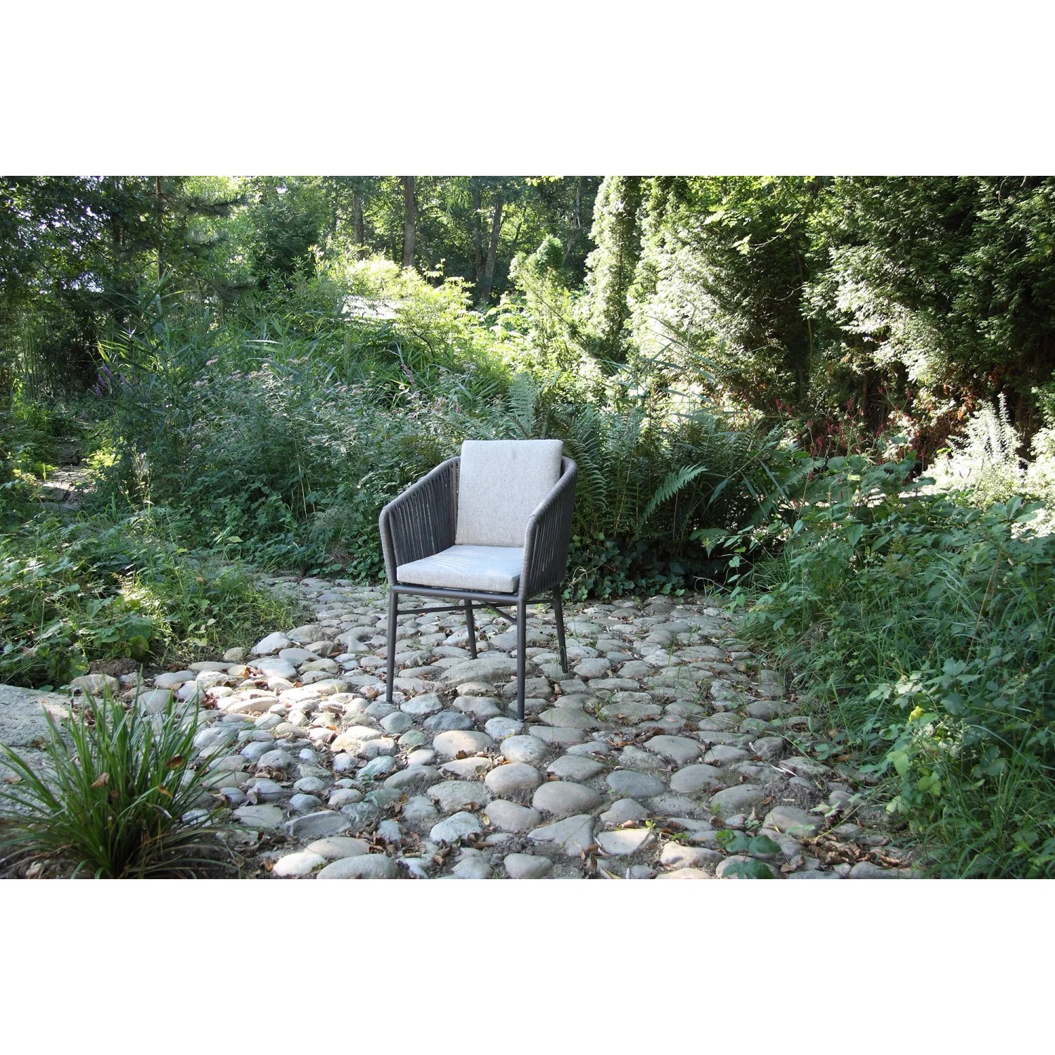 Anthrazitfarbener Acamp Manhattan Armsessel mit Kissen im Garten.