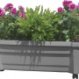 Grauer KHW Pflanzkasten Calypso mit Bewässerungssystem und Rollen, bepflanzt mit Blumen und Farn.