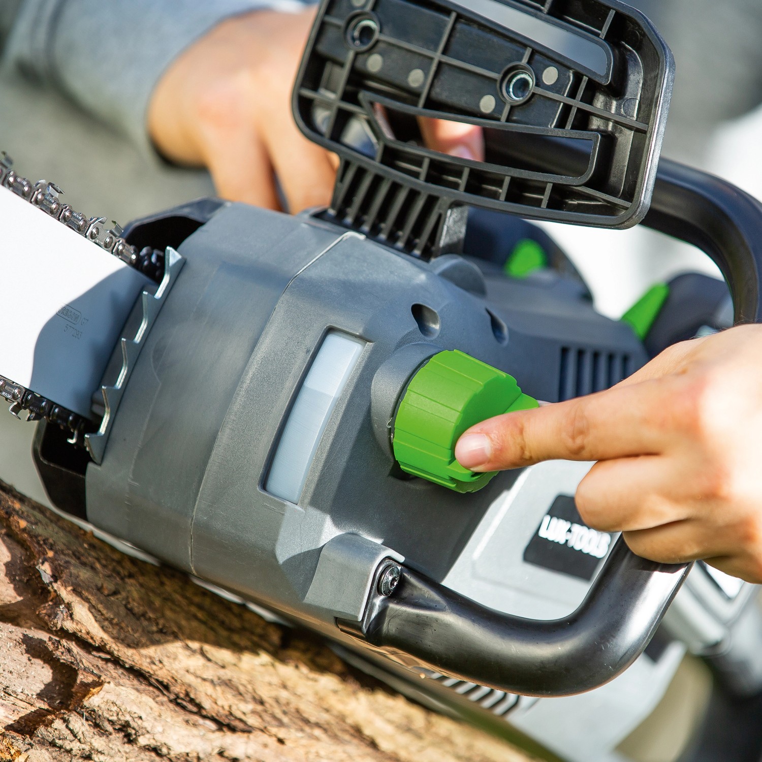 LUX Akku-Kettensäge 1 PowerSystem A-KS-2x20/4/30 beim Einstellen auf einem Baumstamm.