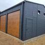 Große Liderstal Fertiggarage aus graphitfarbenem Trapezblech mit drei Sektionaltoren in Goldene Eiche Optik.