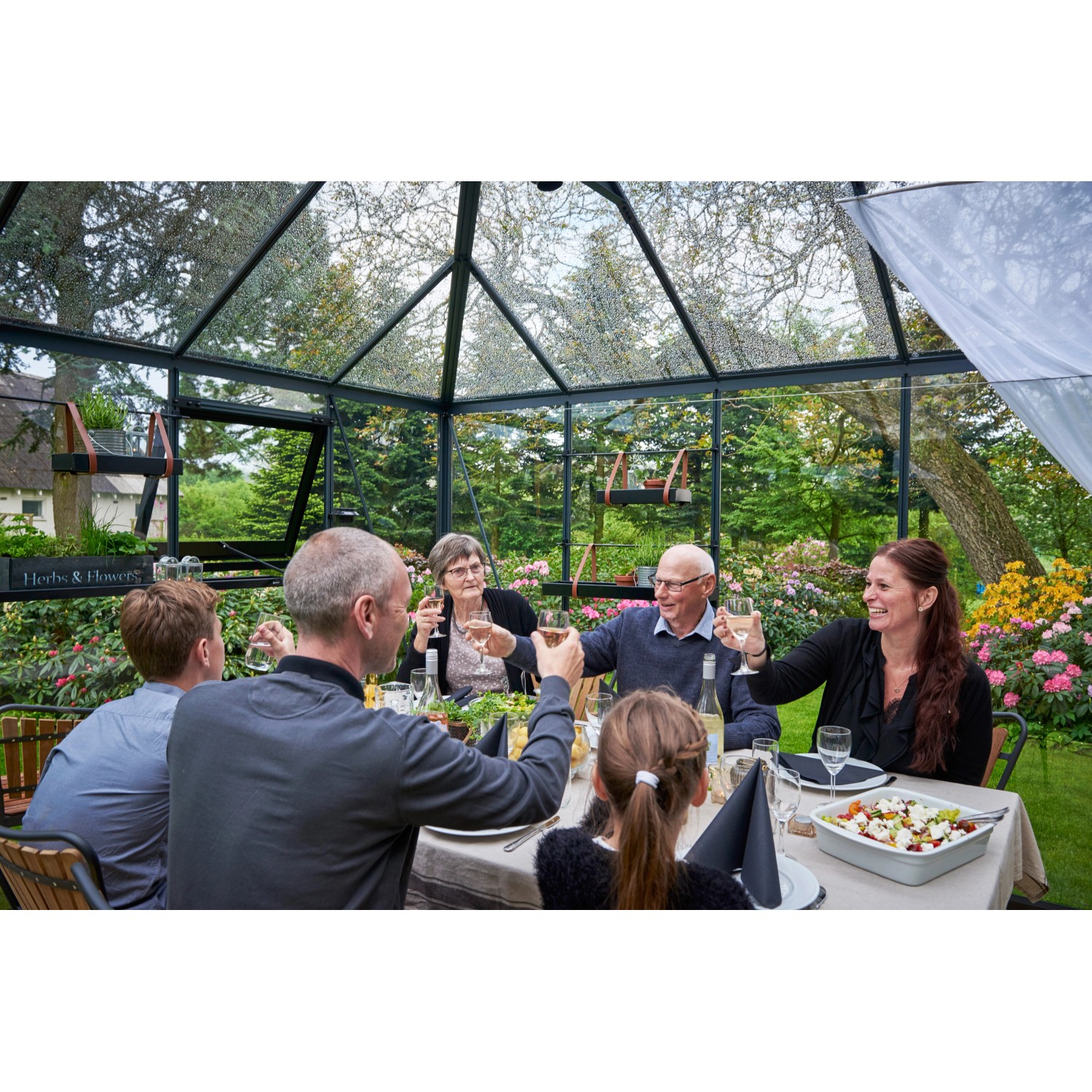 Familie feiert im Juliana Gewächshaus Grand Oase 13 Anthrazit mit Walmdach.