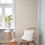 ESTAhome Vliestapete Hellbeige mit zartem Blumenmuster an einer Wand in einem hellen Raum mit Fenster.