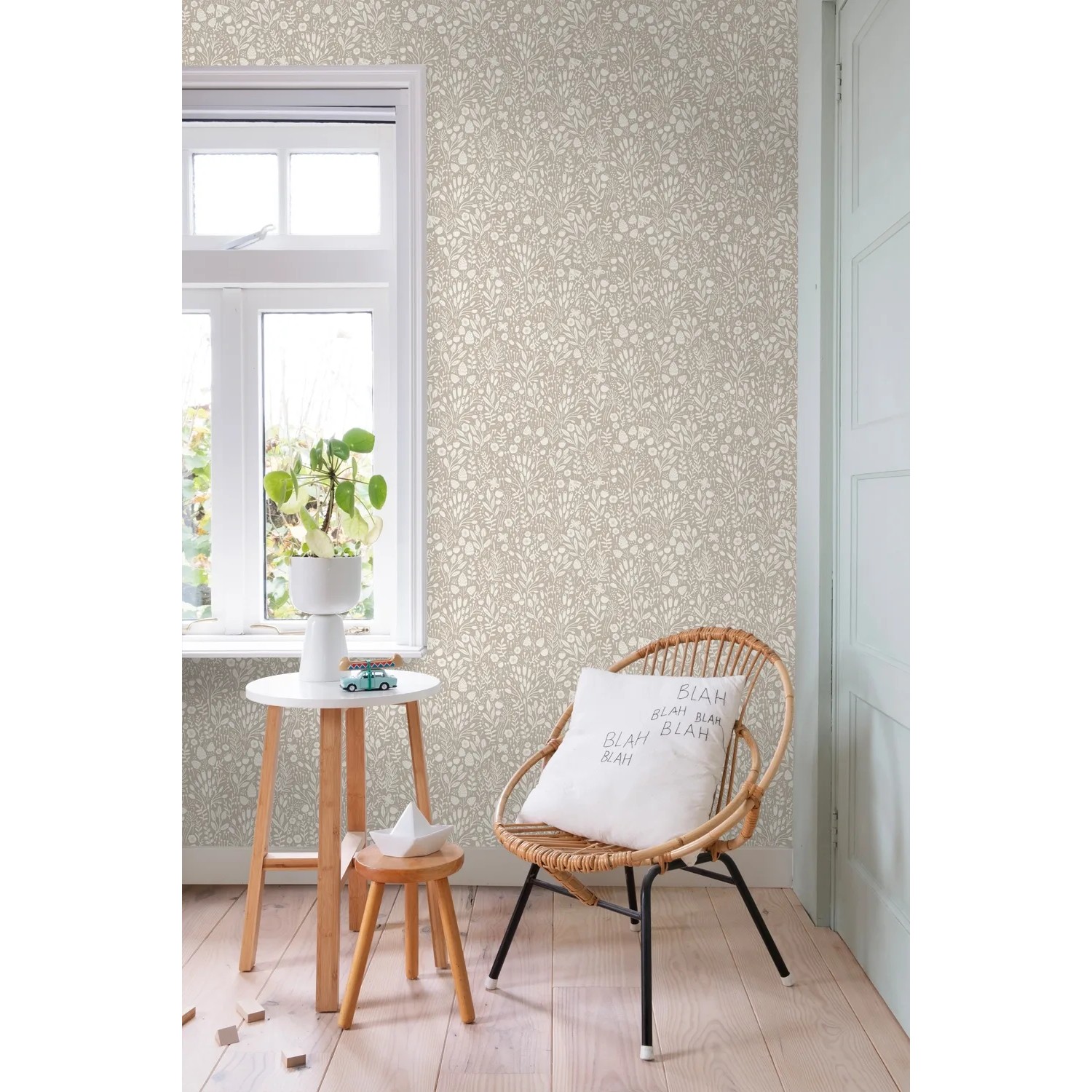 ESTAhome Vliestapete Hellbeige mit zartem Blumenmuster an einer Wand in einem hellen Raum mit Fenster.