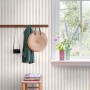 ESTAhome Vliestapete Streifenmuster Beige und Weiß an Wand mit Garderobe und Fenster.