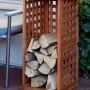 Braunes Kaminholzregal aus Kiefernholz (FSC®) mit Spalieroptik, gefüllt mit Holzscheiten.