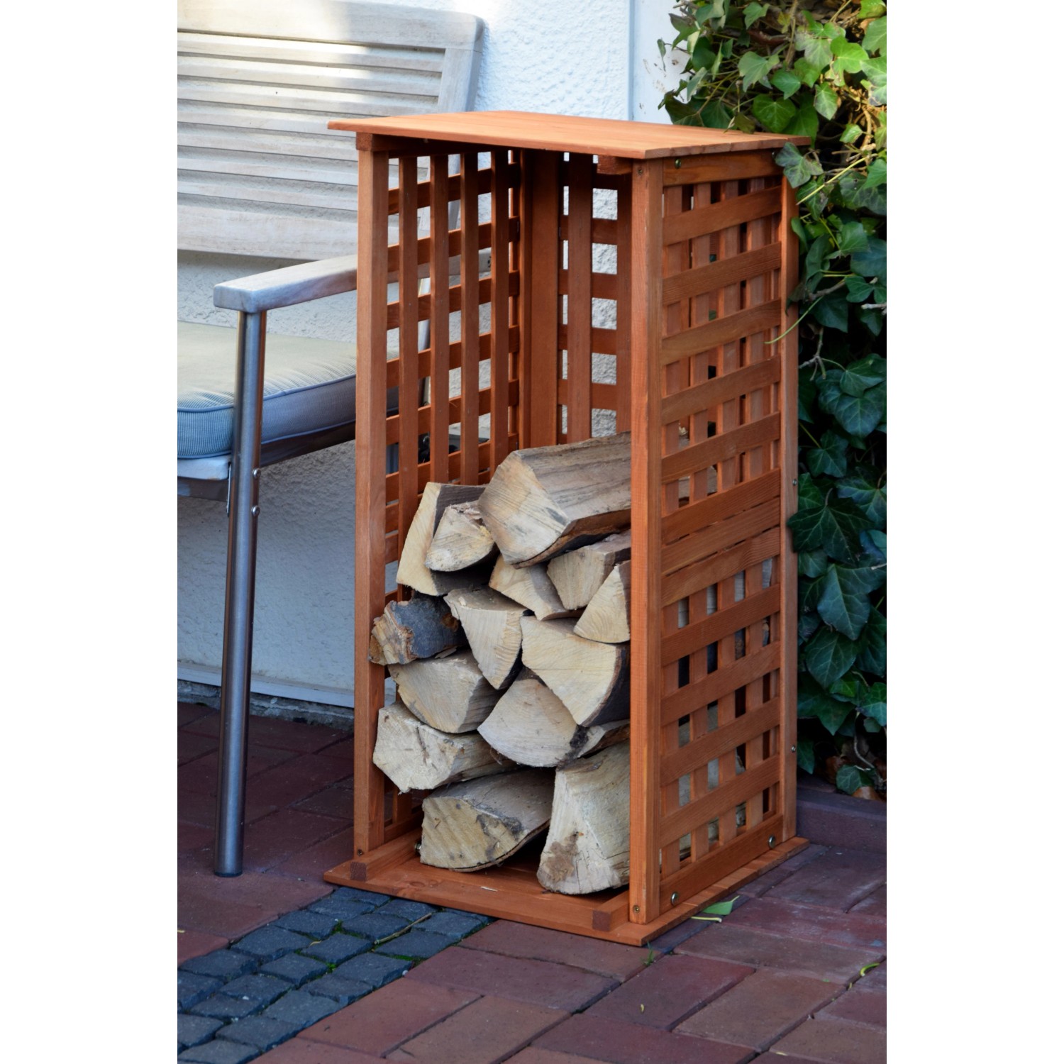 Braunes Kaminholzregal aus Kiefernholz (FSC®) mit Spalieroptik, gefüllt mit Holzscheiten.