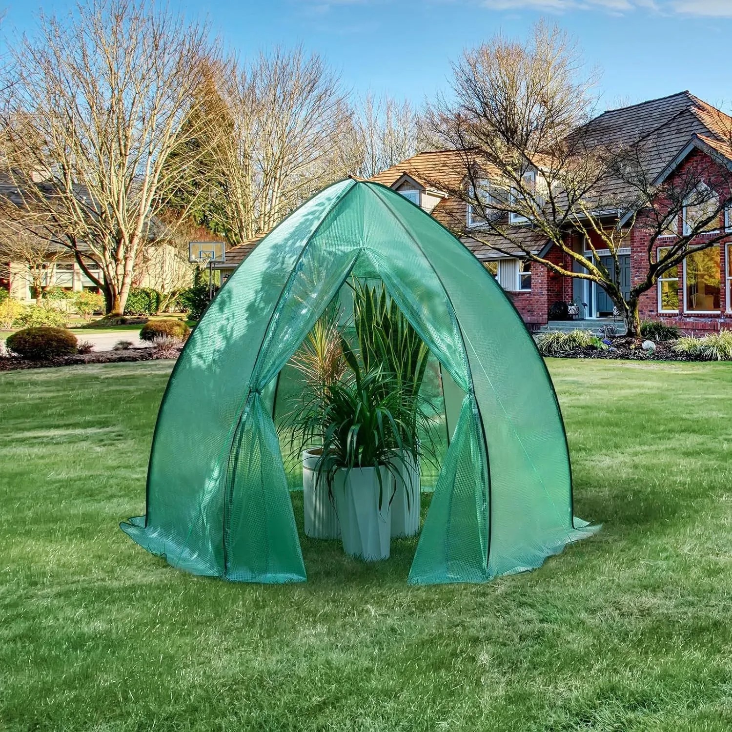 Grünes WOLTU Foliengewächshaus/Überwinterungszelt im Garten mit Pflanzen.