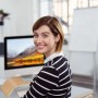Frau am Schreibtisch, Monitor auf gebogenem Bambus Monitorständer. Ergonomische PC-Erhöhung für aufgeräumten Büro-Arbeitsplatz.