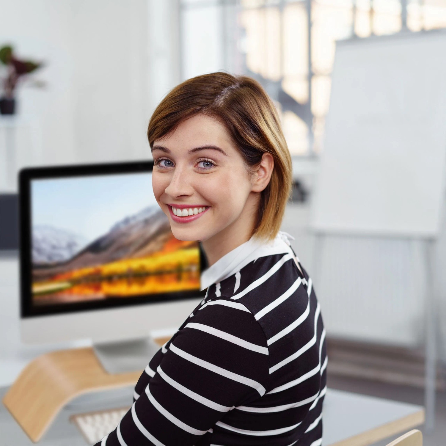 Frau am Schreibtisch, Monitor auf gebogenem Bambus Monitorständer. Ergonomische PC-Erhöhung für aufgeräumten Büro-Arbeitsplatz.