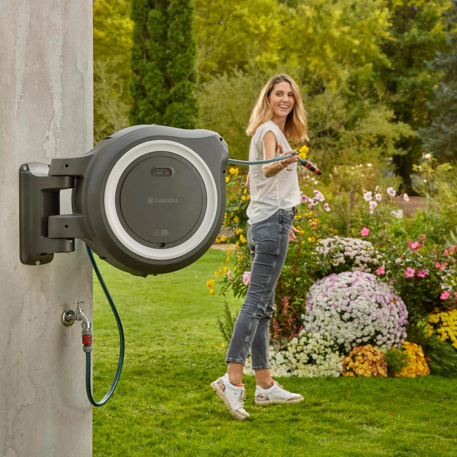 Gardena Akku-Wand-Schlauchbox PowerRoll XXL mit Frau im Garten beim Bewässern.