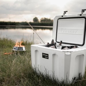 Offene, alpenweiße Petromax Kühlbox (50 l) mit Inhalt in natürlicher Umgebung.