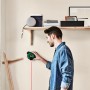 Mann benutzt Bosch Atino Linienlaser an Wand. Das Messwerkzeug projiziert einen roten Laserstrahl.