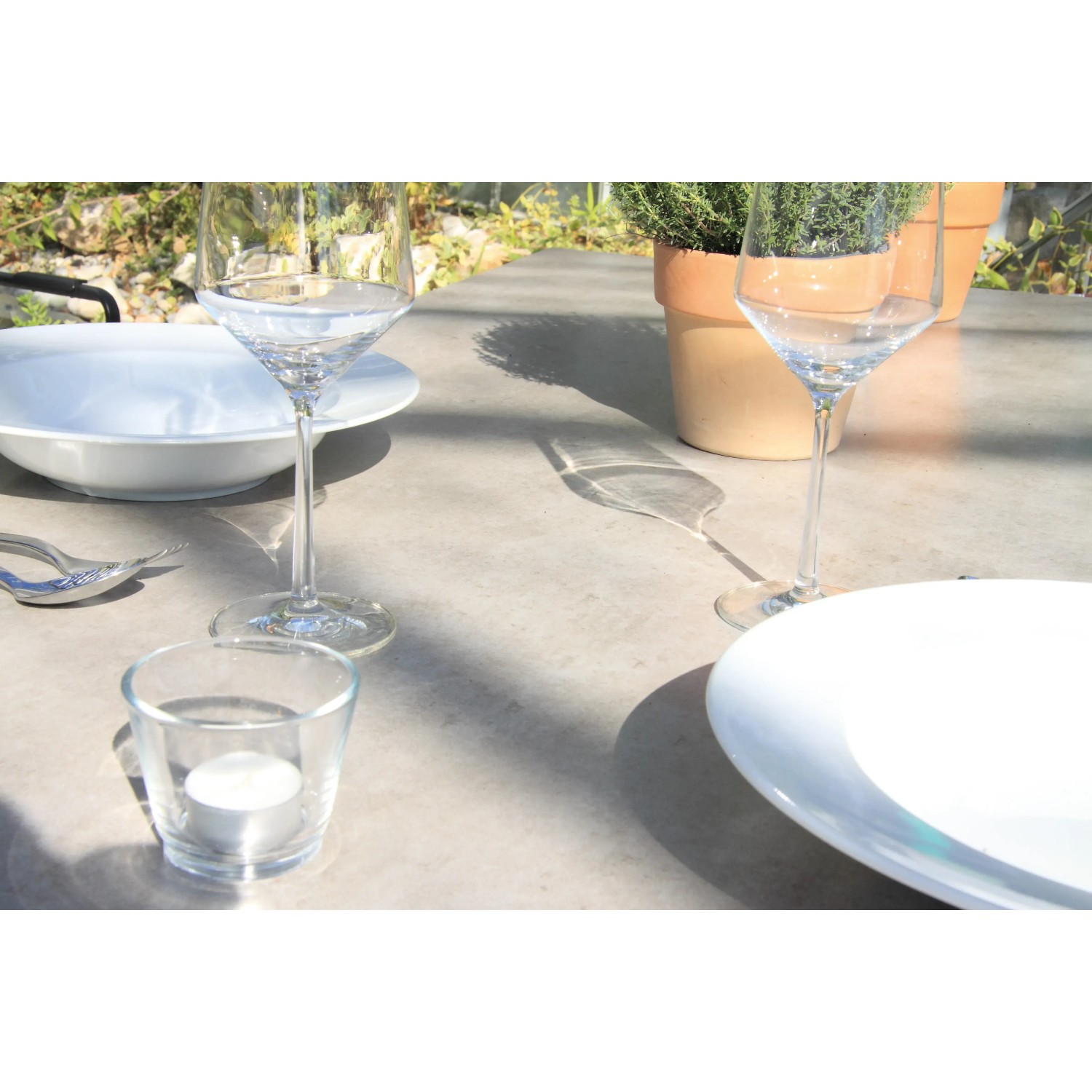 Detailansicht des Acamp Gartenmöbel-Sets Alpha mit Glastisch, Geschirr und Gläsern im Freien.