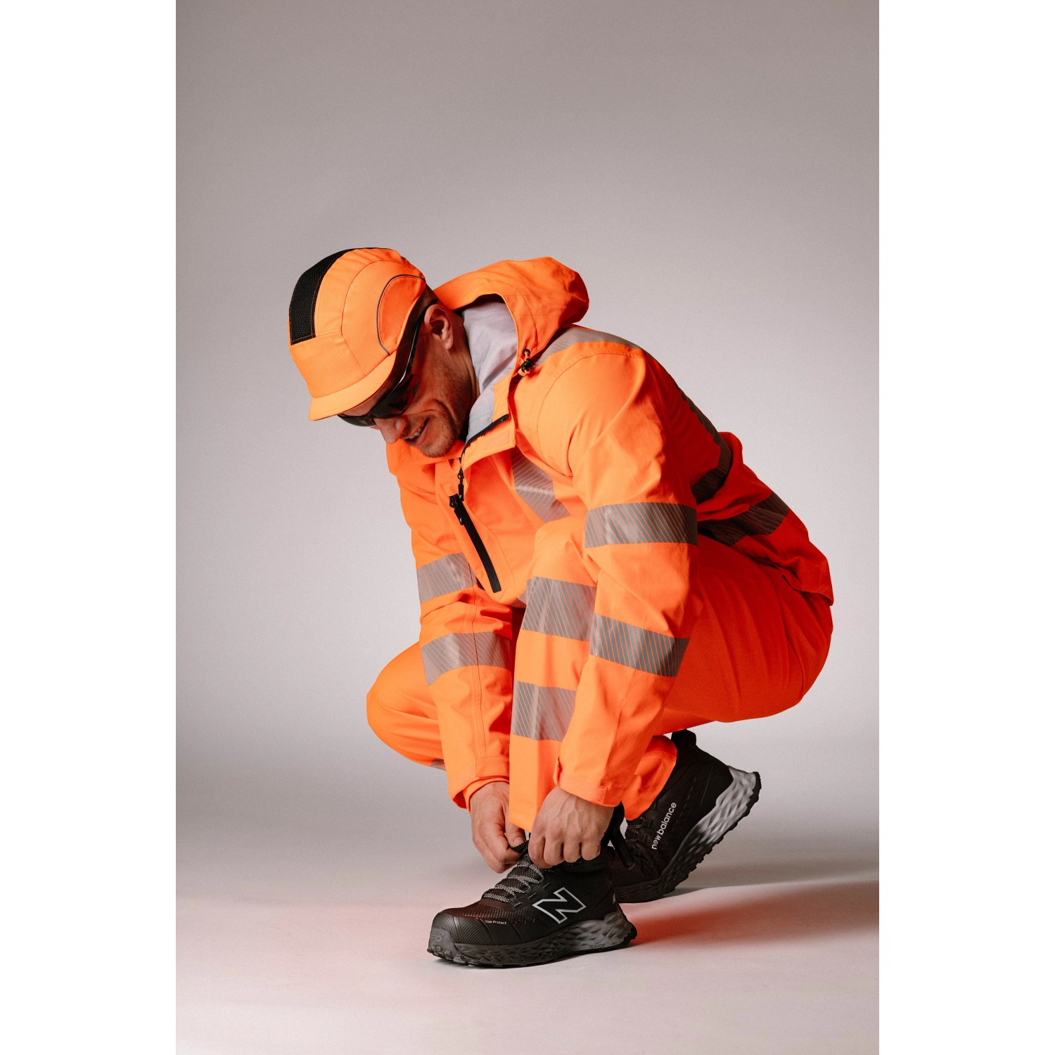 New Balance Sicherheitsstiefel Cremorne Mid S3L, schwarz-grau, Gr. 40, mit orangefarbener Arbeitskleidung.