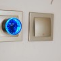 Schwarzer Shelly Smart-Stecker Plug S Gen3 mit blauer LED in Steckdose, Hausautomation.