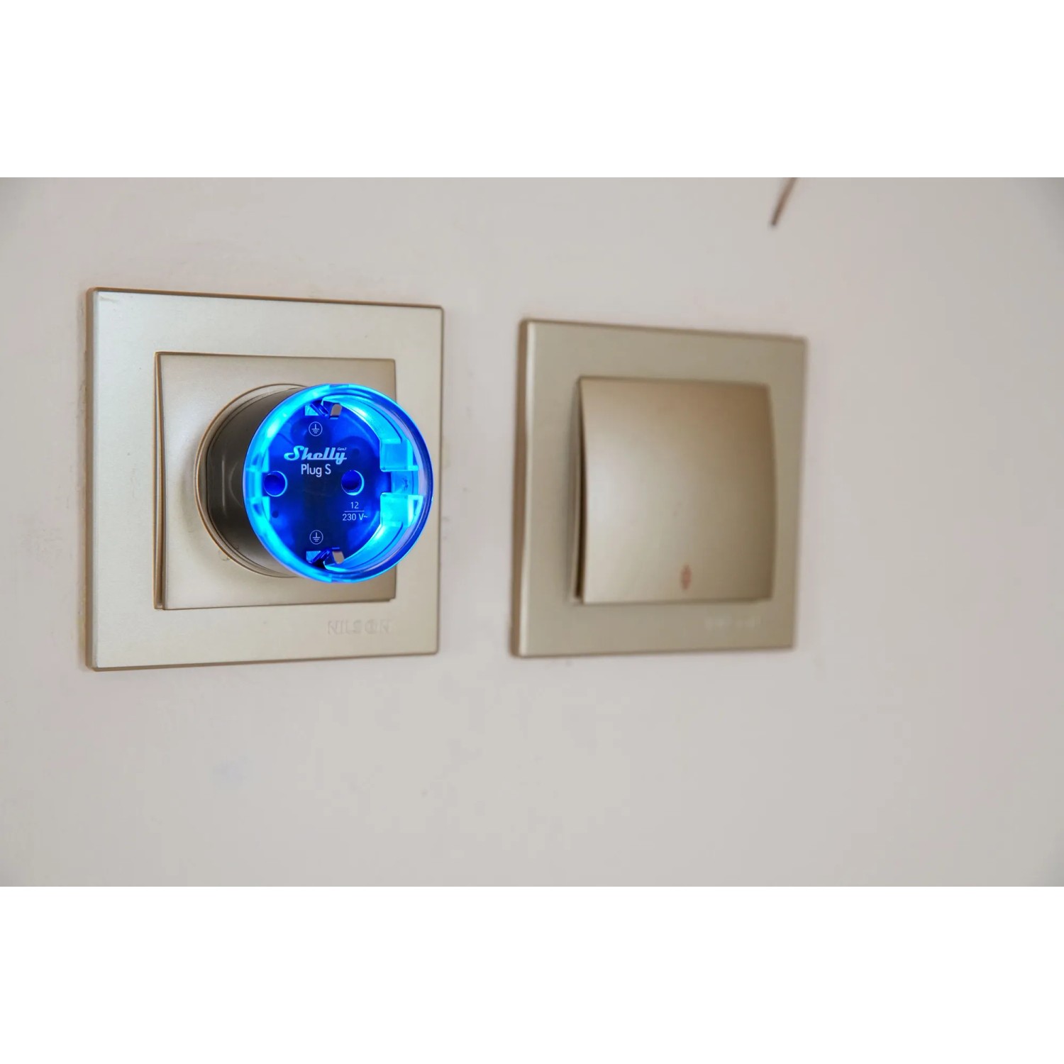 Schwarzer Shelly Smart-Stecker Plug S Gen3 mit blauer LED in Steckdose, Hausautomation.