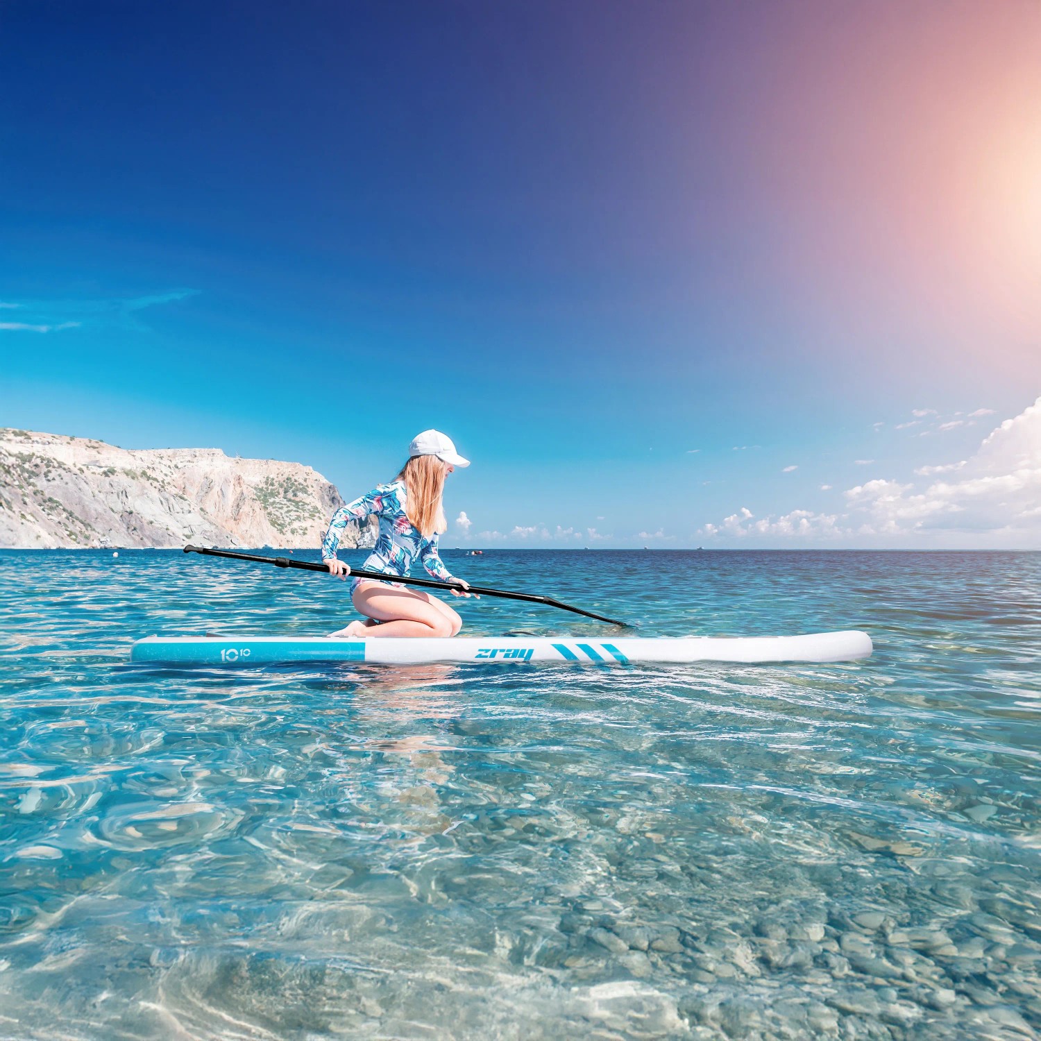 Frau auf blauem ZRAY Stand Up Paddle Board (SUP) im Meer. Komplettset für Wassersport.