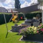 Anthrazitfarbenes Toldoro Sonnensegel Komplettset im Garten mit Möbeln und Spielplatz.