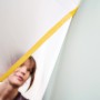 Frau bringt Tesa Abdeckfolie mit Klebeband Easy Cover Perfect+ an Wand an.