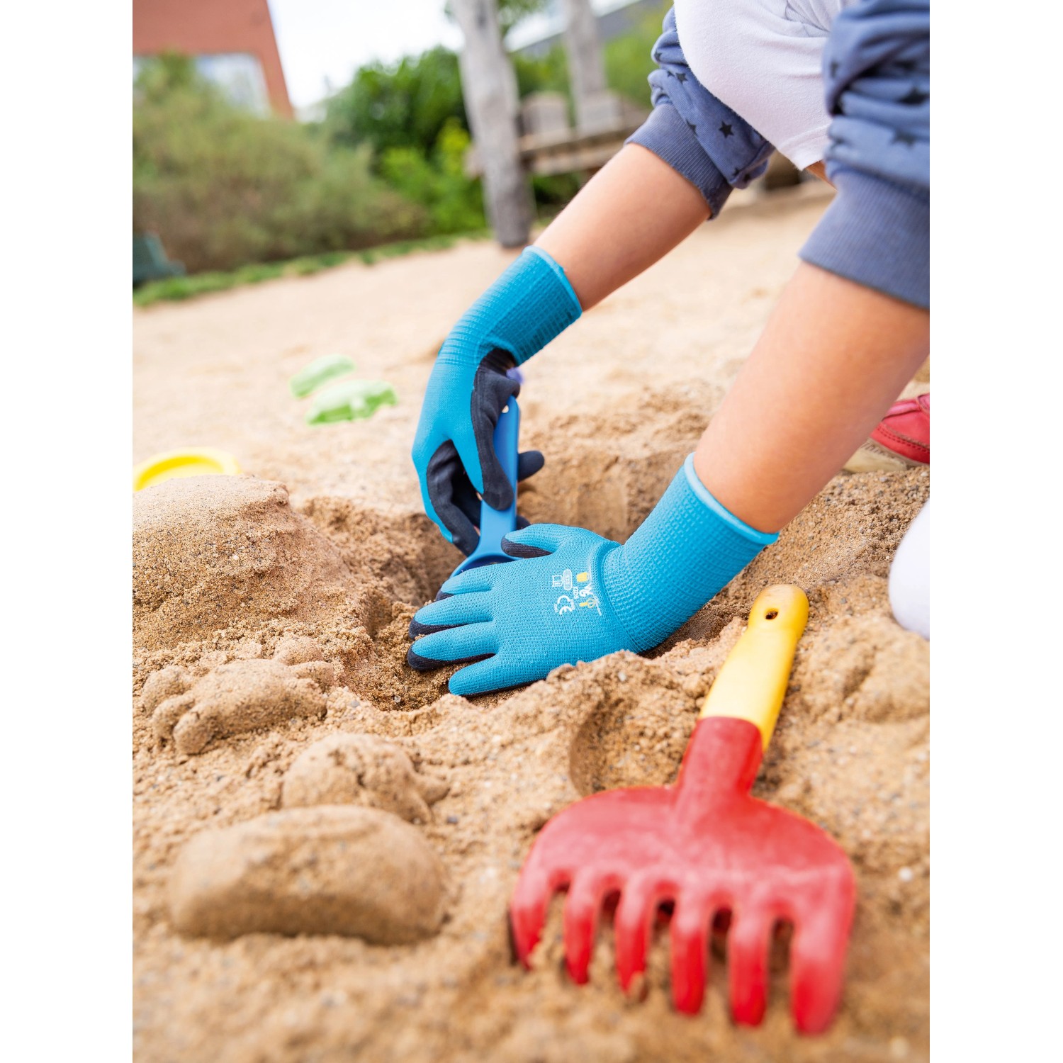 Kind mit blauen Gartenhandschuhen im Sandkasten. Naturlatex-Teilbeschichtung, Größe 4.