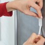 Anbringen eines Tesa Powerstrips Haken Waterproof eckig Edelstahl Large an einer grauen Wand.