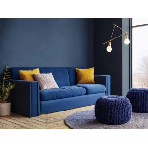 Blaues Sofa mit Kissen und Strickhockern vor blauer Wand.